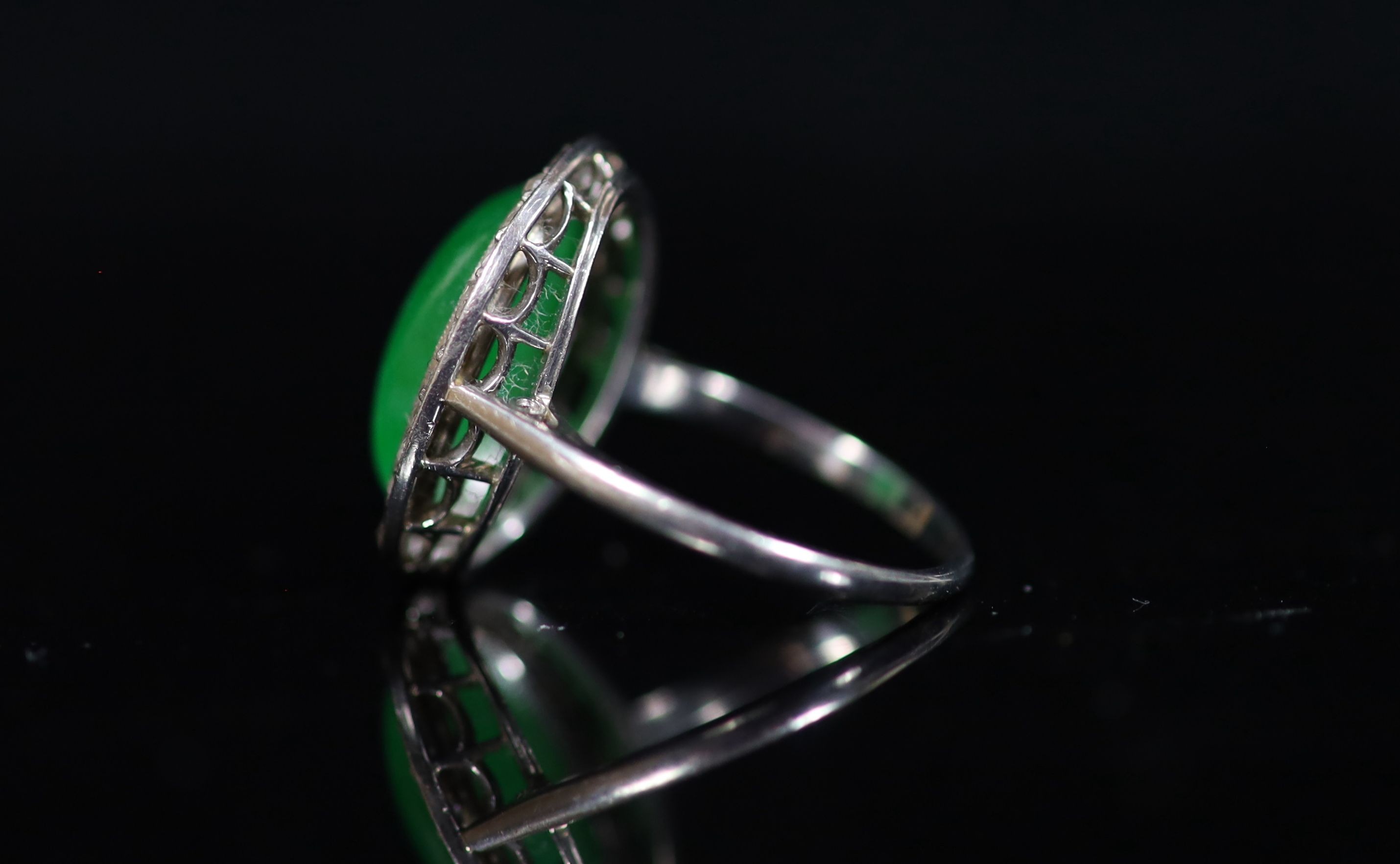 A 1920's 18ct white gold, oval cabochon jadeite and rose cut diamond millegrain set dress ring